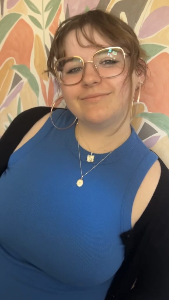 A teenage girl in a blue top is pictured wearing a silver pendant
